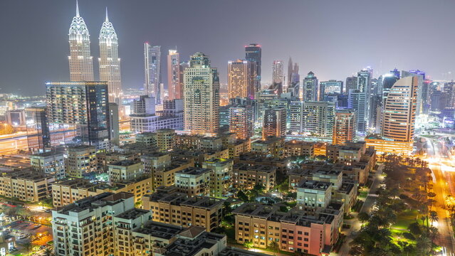Skyscrapers in Barsha Heights district and low rise buildings in Greens district aerial night timelapse.