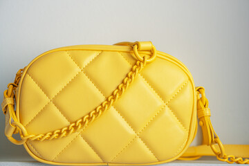 Yellow cross body bag. Ladies bright-colored handbag on gray background.