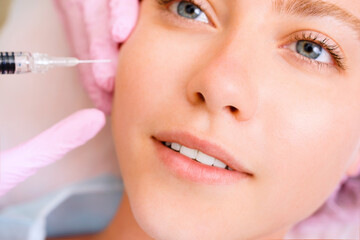 Image of a young beautiful woman dressed as a patient, lying on a couch in a cosmetology clinic.