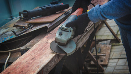 a man is grinding a board. Removing old paint from boards. Carpentry work.