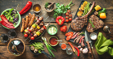 Fototapeta Grilled meats and vegetables on rustic picnic table obraz