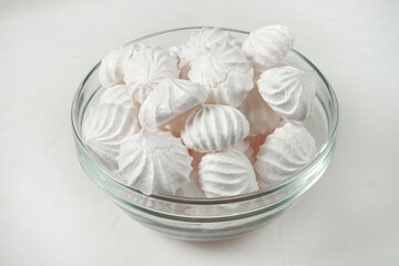 glass vase with French meringue dessert on a gray background, side view.