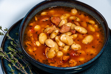 White bean soup served in a blue plate on a white background