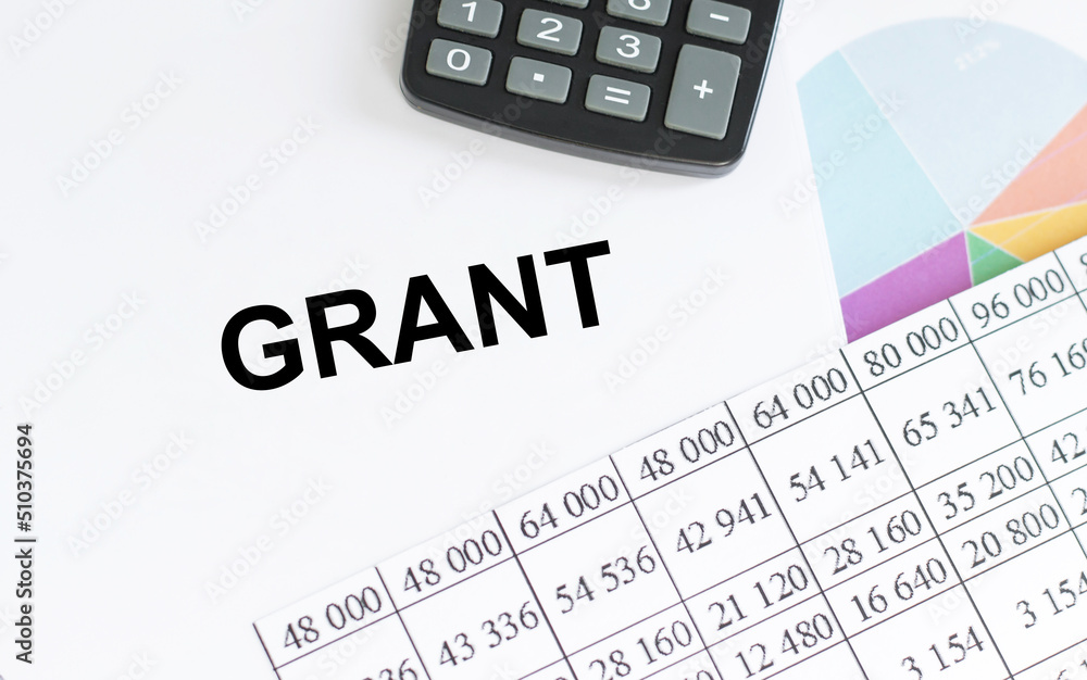 Poster grant text on a notepad on the table among reports and a calculator, a business concept