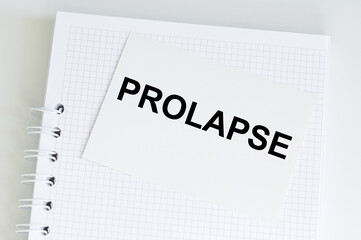 Prolapse inscription on a white card on the background of a rustic notebook on the table, a business concept