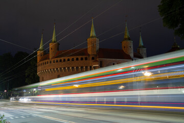 Kraków Barbican by night. Historic fortified gateway of the Old Town of Krakow, Poland. With bus light trails.