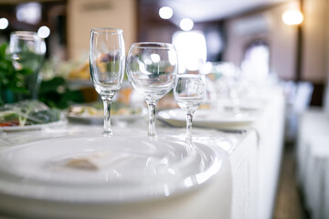 served table in the restaurant crystal clear glass of wine and water, cutlery. Preparation for the event.