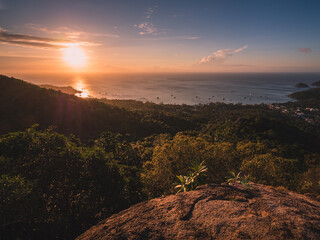 Scenic high angle view of sunset orange sky with sunbeam and Sairee beach in the peaceful evening. Shot from West Coast Viewpoint. Koh Tao Island, Surat Thani, Thailand.