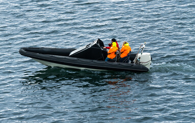 People sailing on the water in an inflatable rubber dingy with a powerful outboard engine.