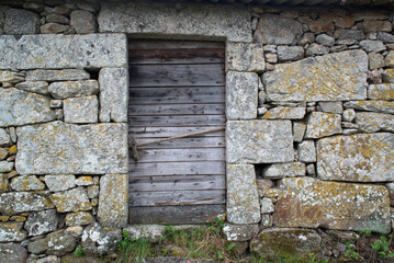 Fototapeta na wymiar Old wooden door in stone wall
