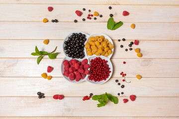 Bowl with natural ripe organic berries with peduncles on wooden table, top view with copy space