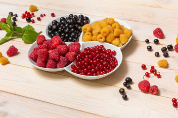 wooden background filled with fresh strawberries, currants and raspberries