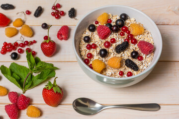 tasty oatmeal with berries on light wooden background
