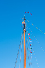 Den Helder, the Netherlands, May 2022. Close up of a mast with flag line against a blue sky. .