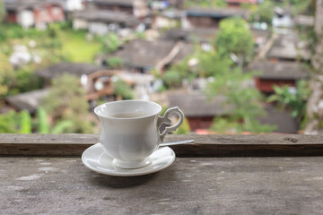 Cup of coffee on wooden table and blurred background.