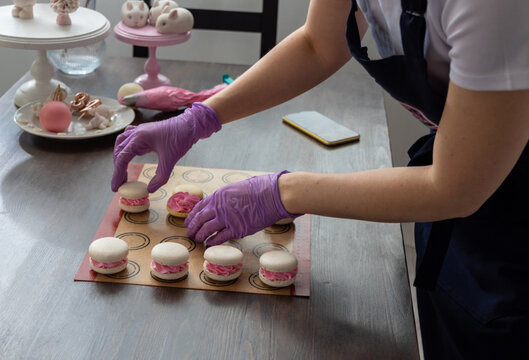 Gloved hands collect macaroons on the table. Selective focus. Photos about confectioners, food, hobbies.