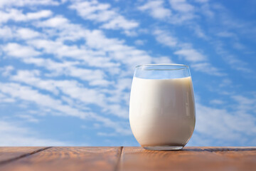 glass of milk on table with blue sky and clouds