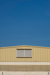 Aluminum louvers on steel wall of warehouse building against blue clear sky in minimal style and vertical frame