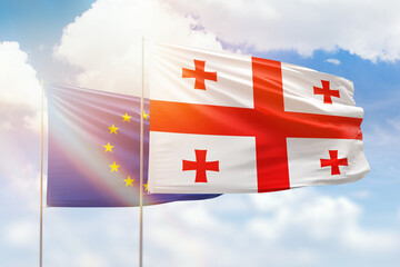 Sunny blue sky and flags of georgia and european union