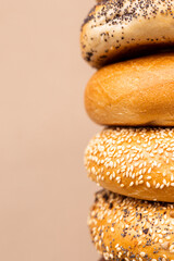 large number of different bagels in hands on a beige background