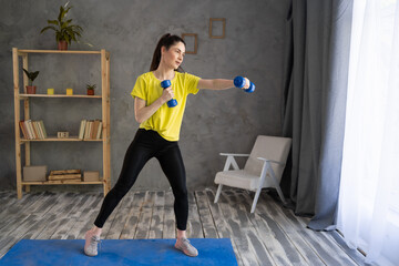 Fototapeta na wymiar young athletic woman exercising with dumbbells at home. Sport, healthy lifestyle