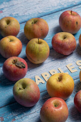 Yellow and red tasty raw apples fruit with apples wooden word written on a blue board