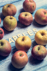 Many yellow and red apples fruit with apples word written on wooden letters on a blue background