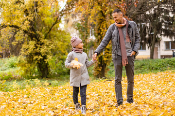 Fototapeta premium Happy father and daughter in autumn park on yellow leaves