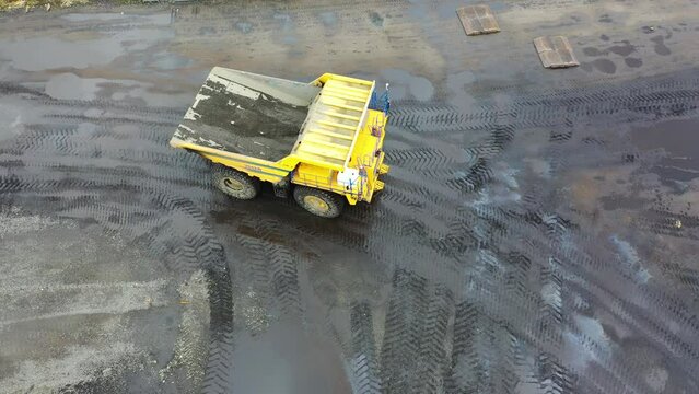 Big BELAZ dump truck rides through a dirty quarry