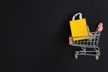 Small paper shopping bags with shopping cart on black background