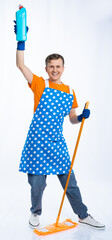 a man in a blue apron, rubber gloves, an orange t-shirt, jeans and white sneakers holds a mop and...