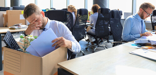 Sad dismissed worker are taking his office supplies with him from office