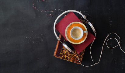 audio book concept with stack of books, cup of espresso coffee and headphones flat lay, good copy space.