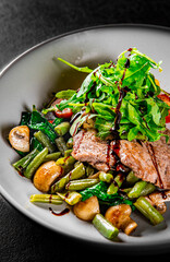 Roastbeef salad with green beans and mushroom in a bowl on Dark grey black slate background