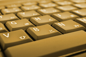 Japanese typing. Light brown laptop keyboard. Symbols on buttons of hiragana. Electronic commerce in Japan. IT technologies and data storage. Dark yellow tinted computer background or wallpaper. Macro