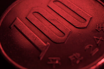 Translation: year of issue 2012. Japanese 100 yen coin close-up. Dark red tinted background....