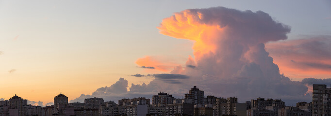 Huge cumulus cloud in form of explosion over residential city district in summer evening.