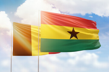 Sunny blue sky and flags of ghana and belgium