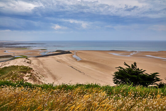 Image of Carteret Plage with the headland in the foreground, break water and sand dunes. Normandy, France.