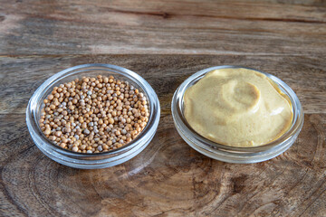 Close-up of mustard seeds and yellow mustard in glass bowls