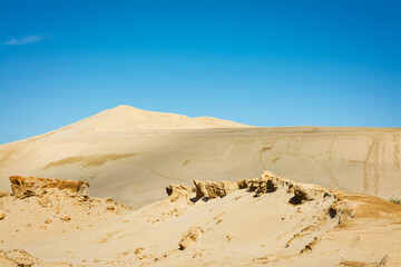 Fototapeta na wymiar Desert-like landscape of the Giant sand dunes, Te Paki, on a beautiful summer day. Bizzarre sand formations and classic cones under clear blue sky. Northland, New Zealand