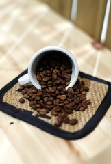 granos de café tostado saliendo de una taza