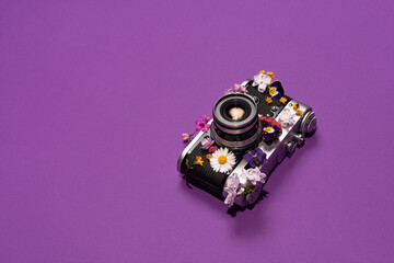 Vintage camera with flowers on a purple background  