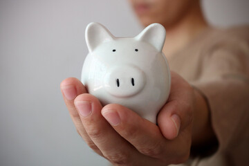 Working man holding piggy bank carefully, saving money for retirement concept.