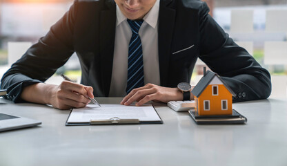 Signing of a contract between a real estate agent or home developer that presents a contract for the sale of a home to an advisor. Real estate contract signing concept