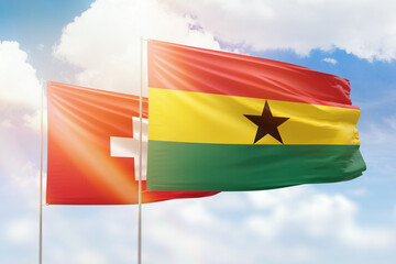 Sunny blue sky and flags of ghana and switzerland