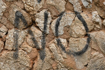 Die Buchstaben NO auf einer rustikalen Sandsteinwand