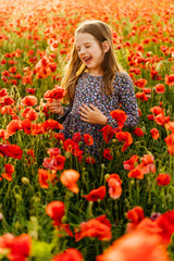 Adorable little girl in dress playing in poppy flower field
