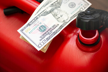 Red jerry fuel can and dollar bills closeup