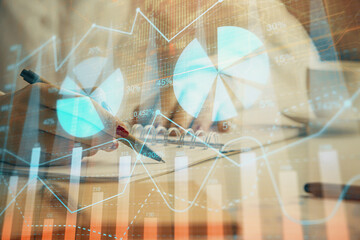 Double exposure of woman's hands making notes with forex graph hologram. Concept technical analysis.